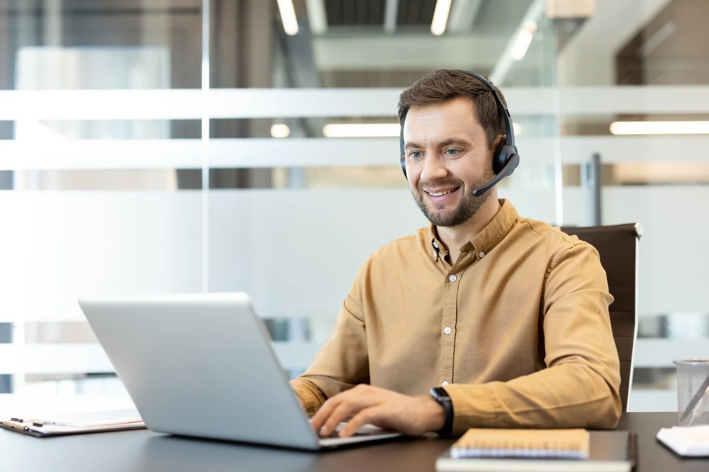 A professional wearing a headset while working at a laptop