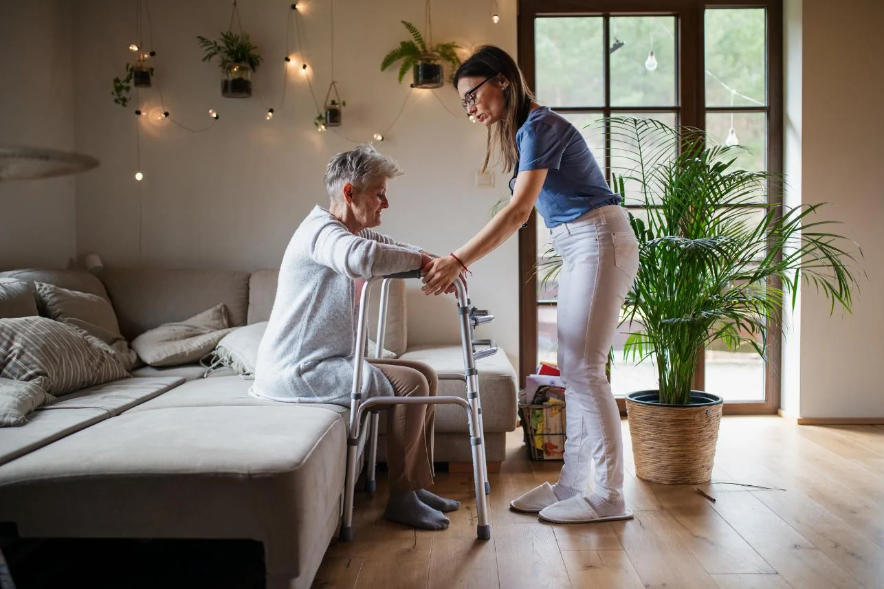 A support worker assisting an older adult using a walking frame